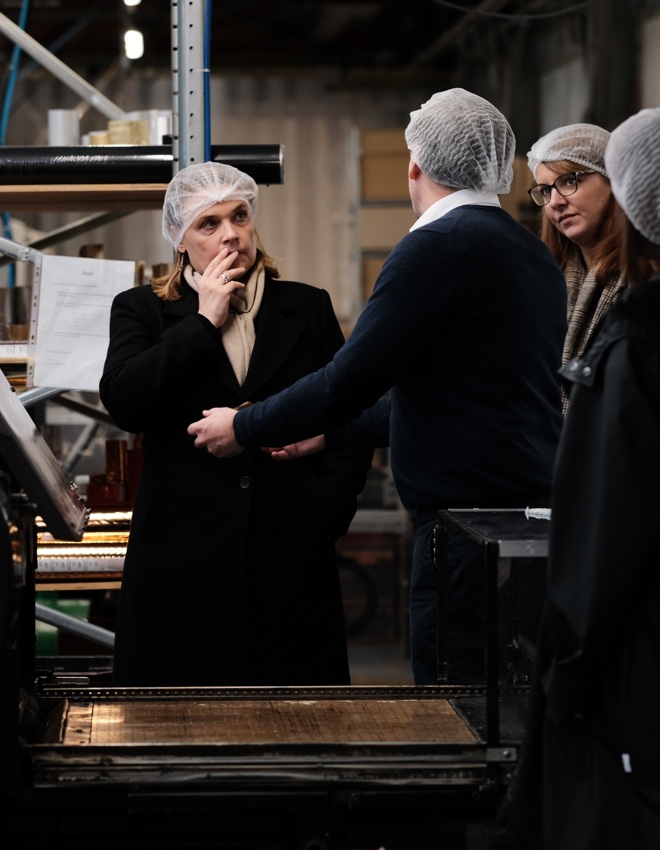 4 personnes portant des filets pour cheveux, discutant dans un atelier de production.