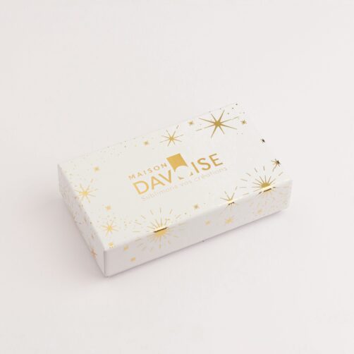 Plumier de chocolats ouvert avec intérieur doré révélant un assortiment de bonbons en chocolat.