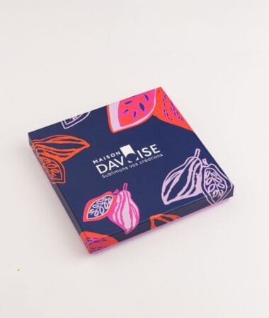 Boîte carrée Maison Davoise bleu nuit ornée d’illustrations de cabosses stylisées.